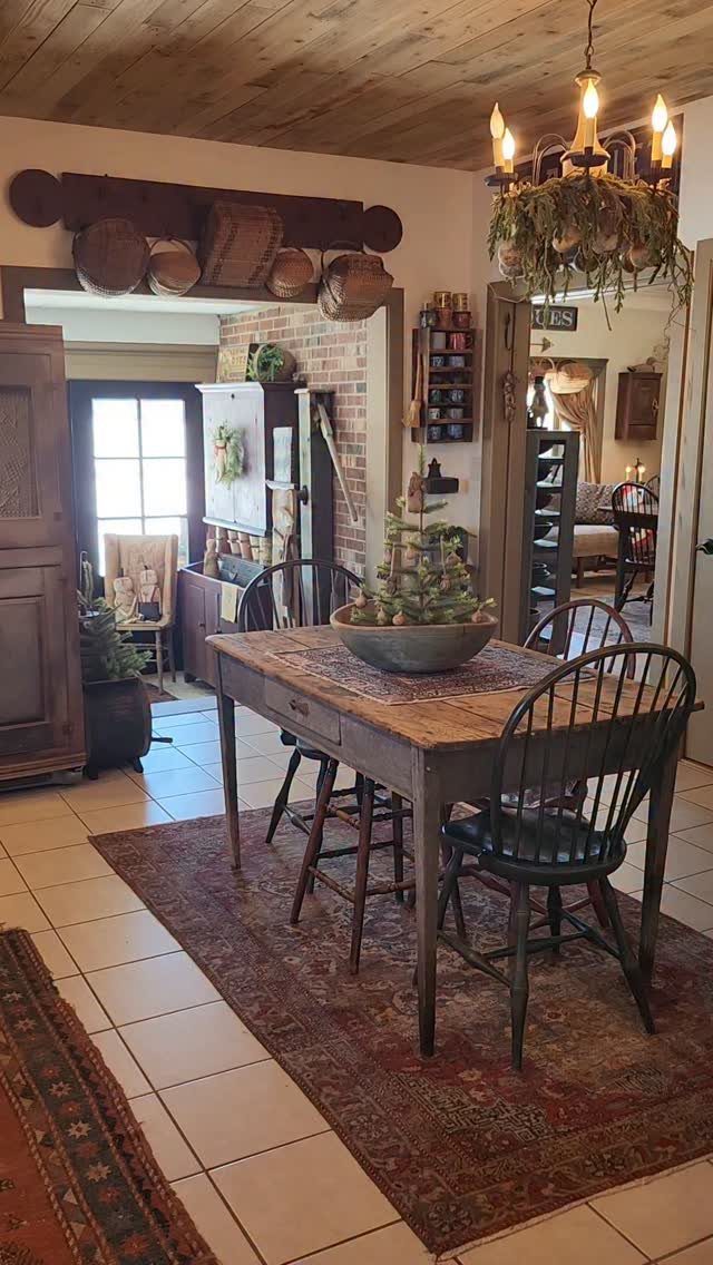 Rustic dining room with wooden table, black chairs, and a red patterned rug.