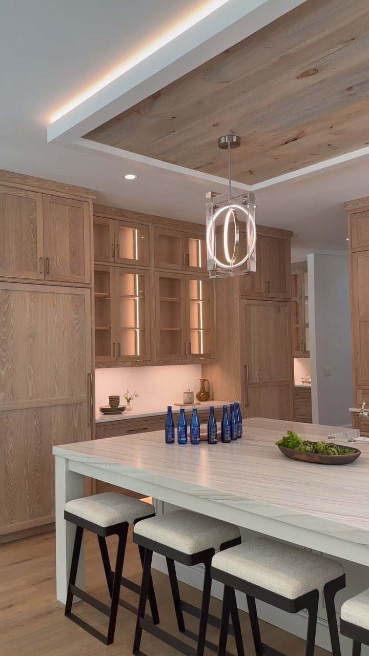 Light wood custom kitchen cabinetry with a white marble island and modern lighting.