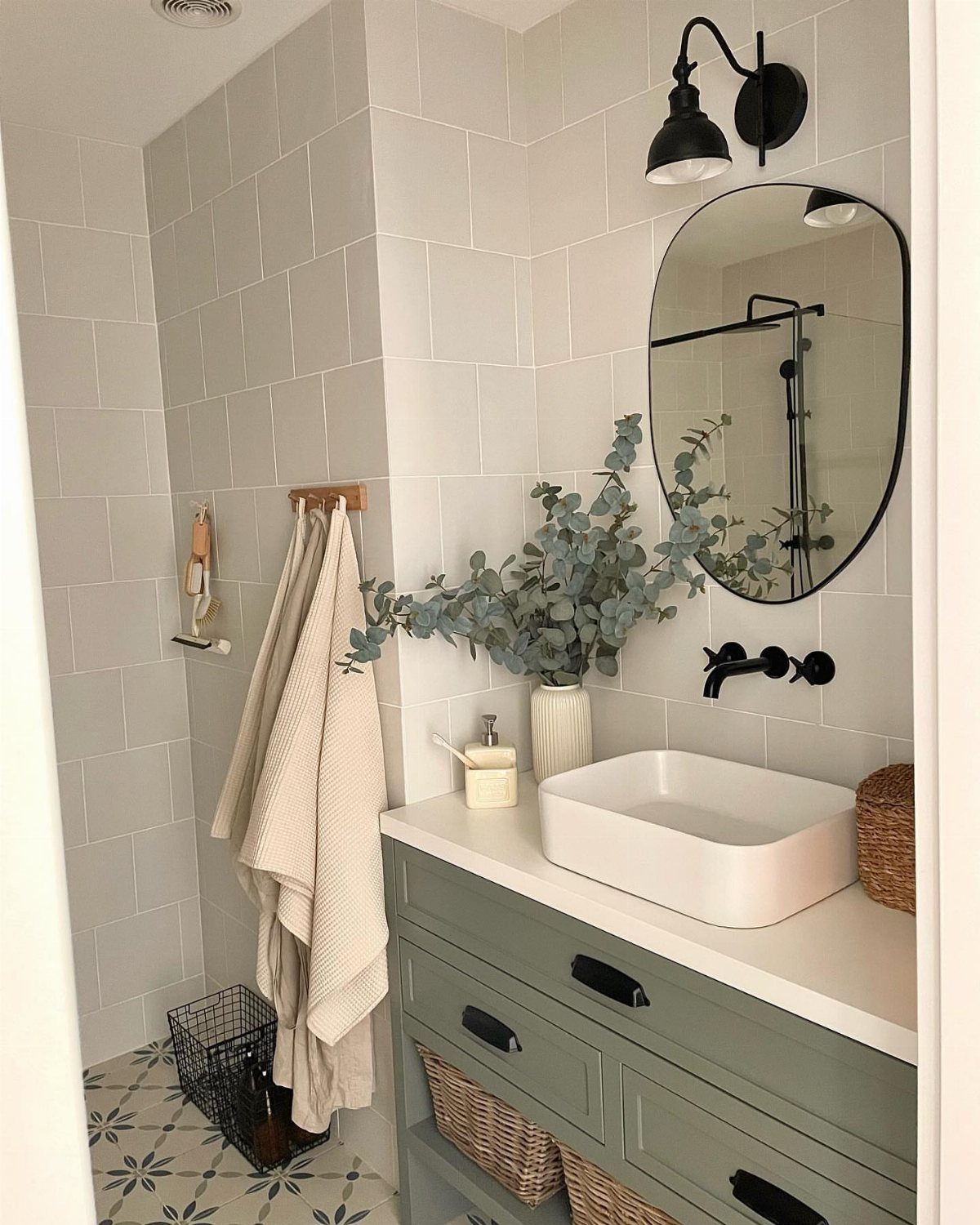 Sage green bathroom vanity with white vessel sink and round mirror