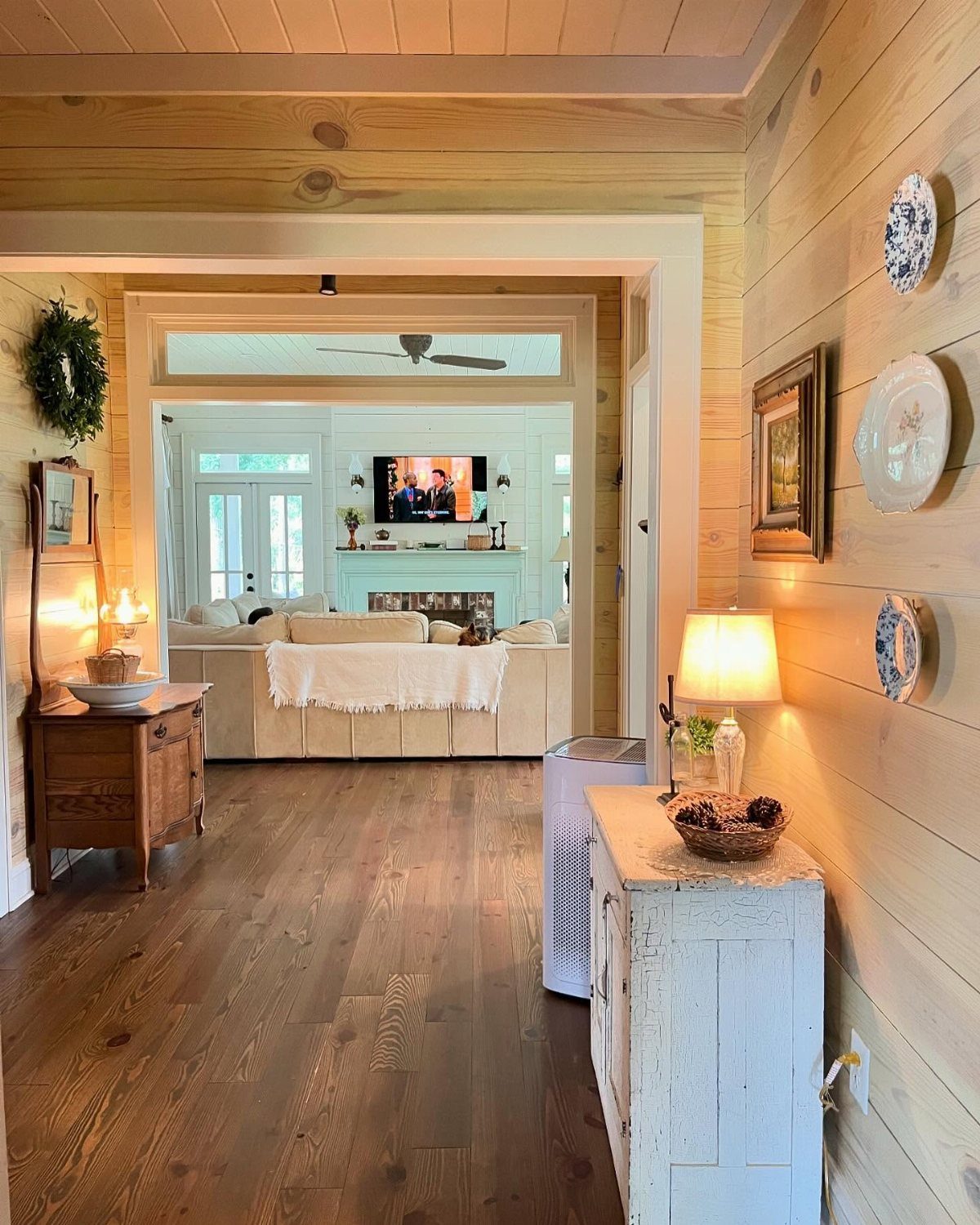Light wood shiplap walls in a hallway leading to a bright living room