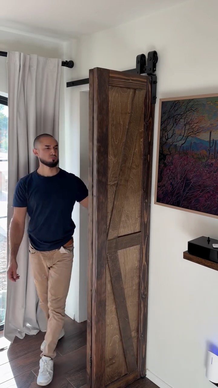Rustic wooden sliding barn door with black hardware in a bright modern interior