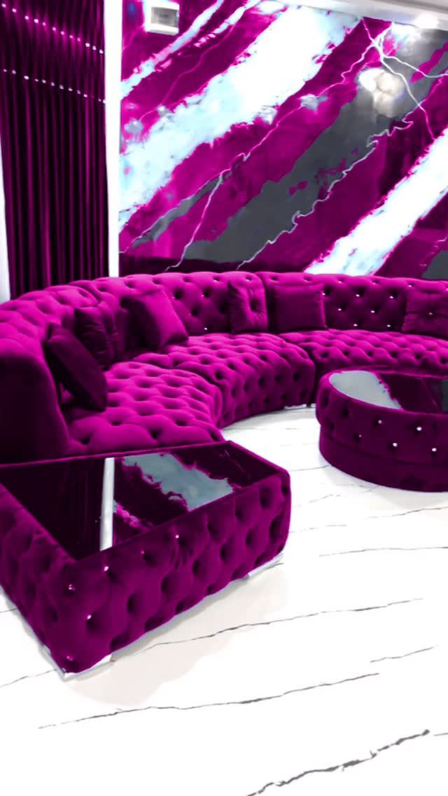 Purple tufted velvet sectional sofa and matching tables in a modern marble room.