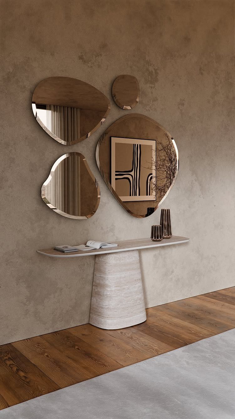 Organic shaped mirrors on a beige wall above a modern white pedestal table.