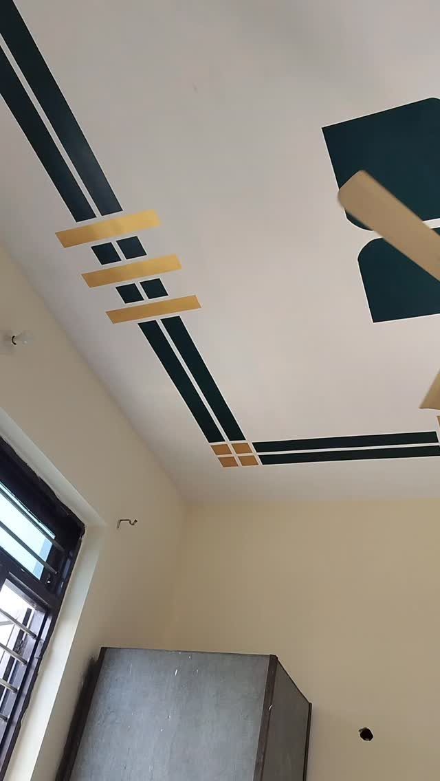 White ceiling with dark teal and gold geometric painted patterns and a fan.