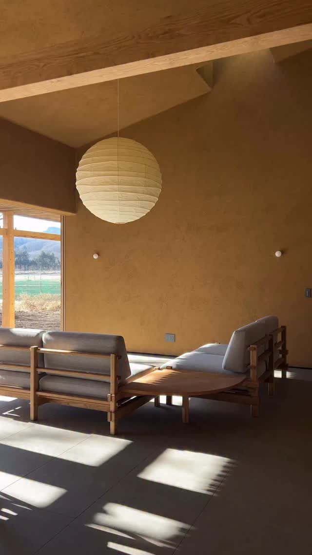 Wooden framed sofa and coffee table in a minimalist room with paper lantern.