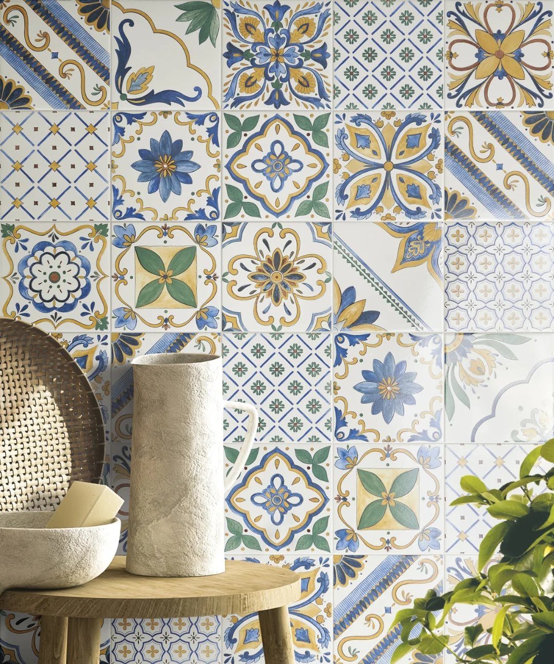 Patterned Mediterranean ceramic tiles in blue and yellow with stone accessories on wood.