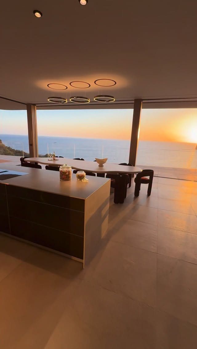 Modern dining area with an ocean view during a golden sunset.