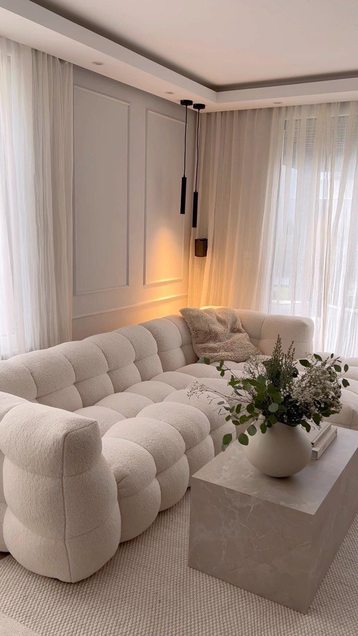 White modular tufted sofa and stone coffee table in a neutral modern living room