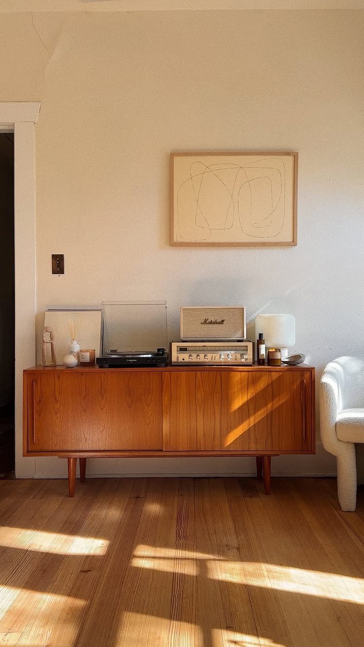 Mid-century modern wooden sideboard with vintage radio and record player against white wall