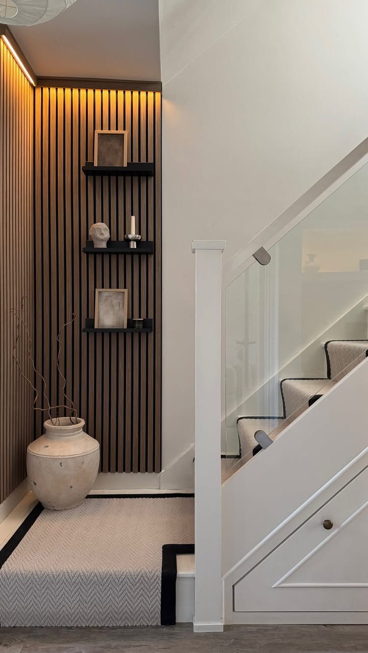 Vertical wood slat wall panels with black shelves and a beige ceramic vase.