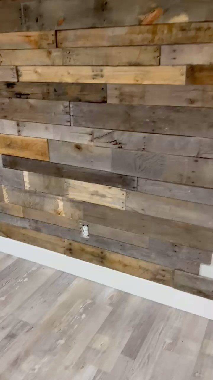Reclaimed wood accent wall with multi-toned horizontal planks and white baseboard.