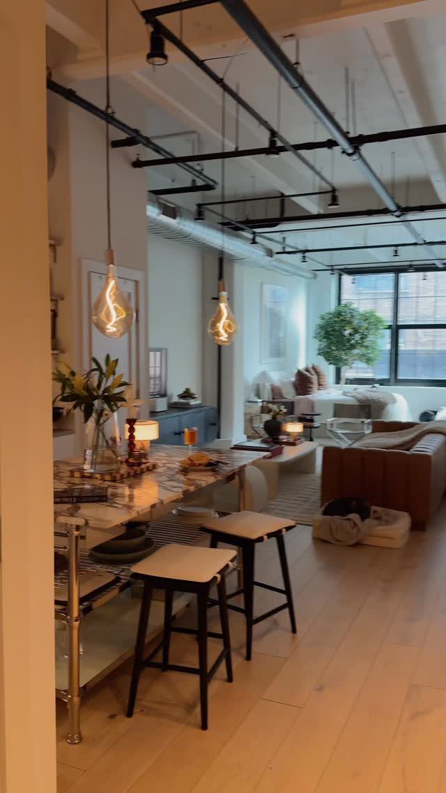 Industrial loft interior with exposed pipes, wooden floors, and a leather sofa.