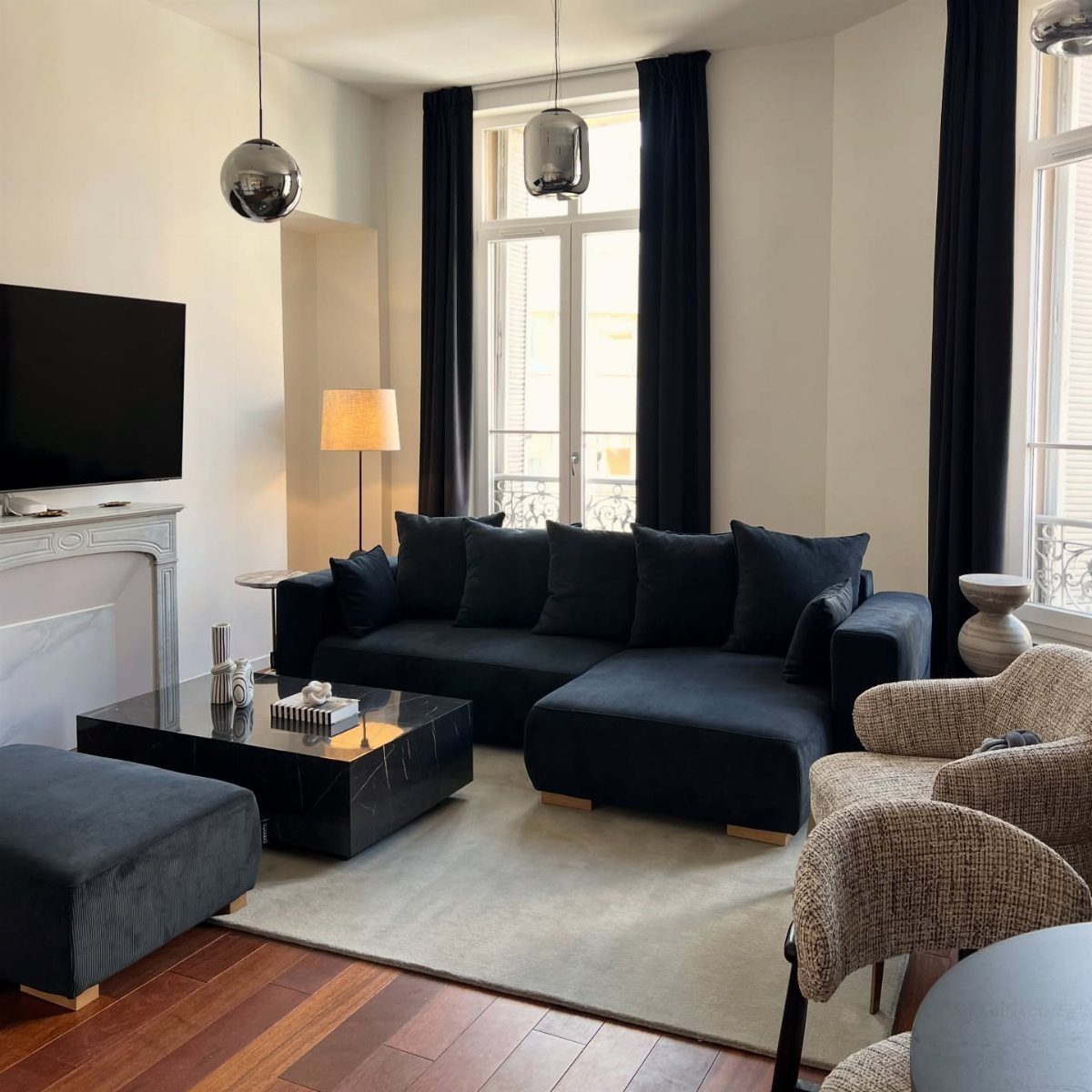 Navy blue sectional sofa and beige armchairs in a modern white living room