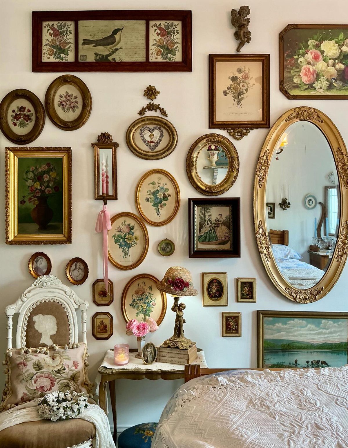 Vintage gallery wall with gold framed floral paintings and a large oval mirror.
