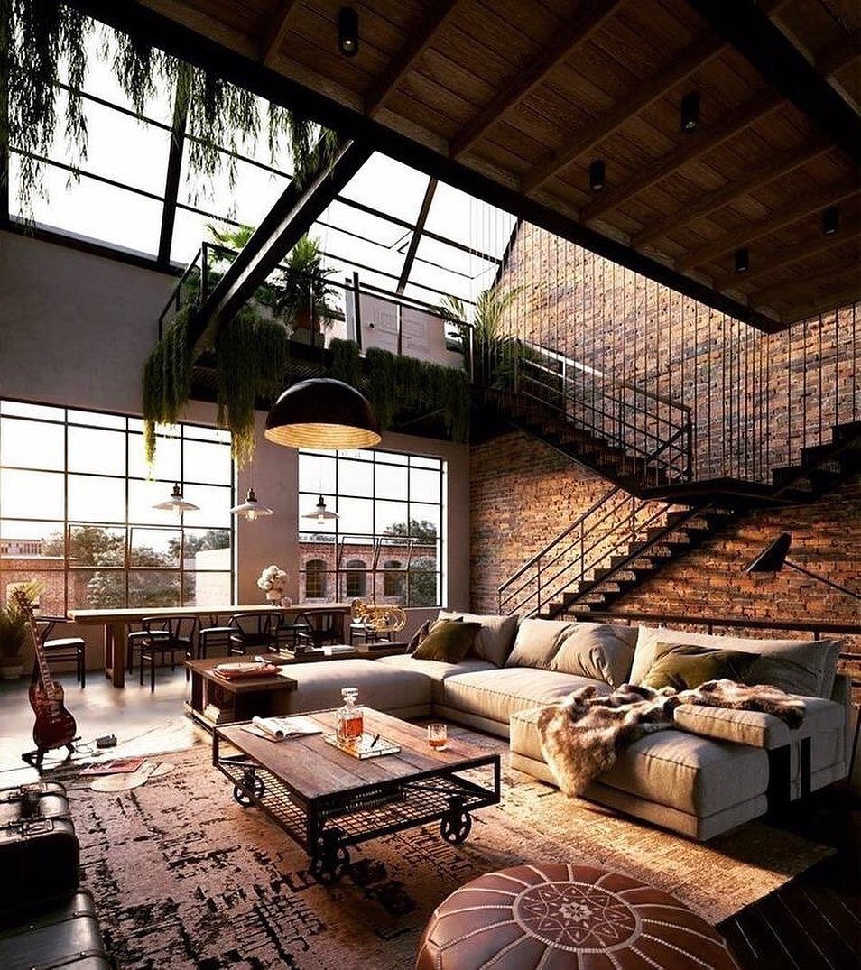 Industrial loft interior with exposed brick, large windows, and a modern grey sectional sofa.