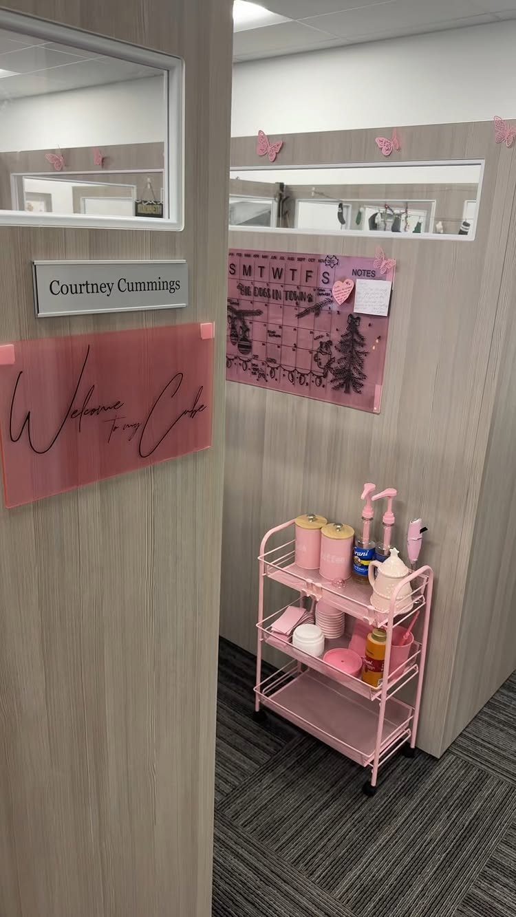 Pink themed office cubicle with a rolling cart and pink wall decorations.
