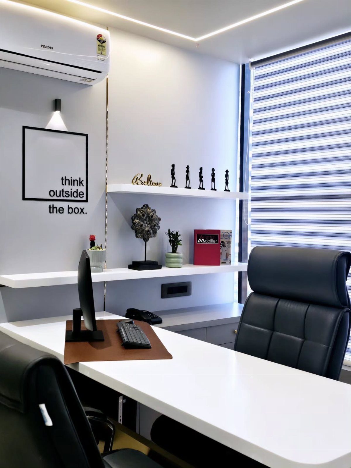 Modern office desk with a framed motivational quote and minimalist shelf decor.