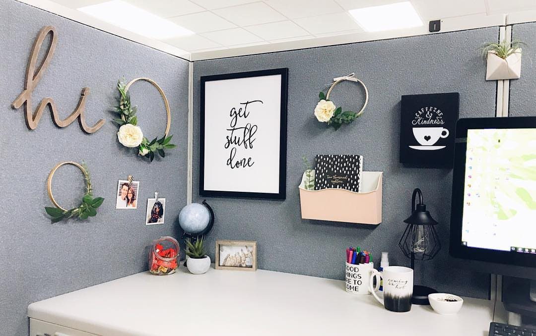 Decorated office cubicle walls featuring floral hoops, a framed quote, and personal photos.