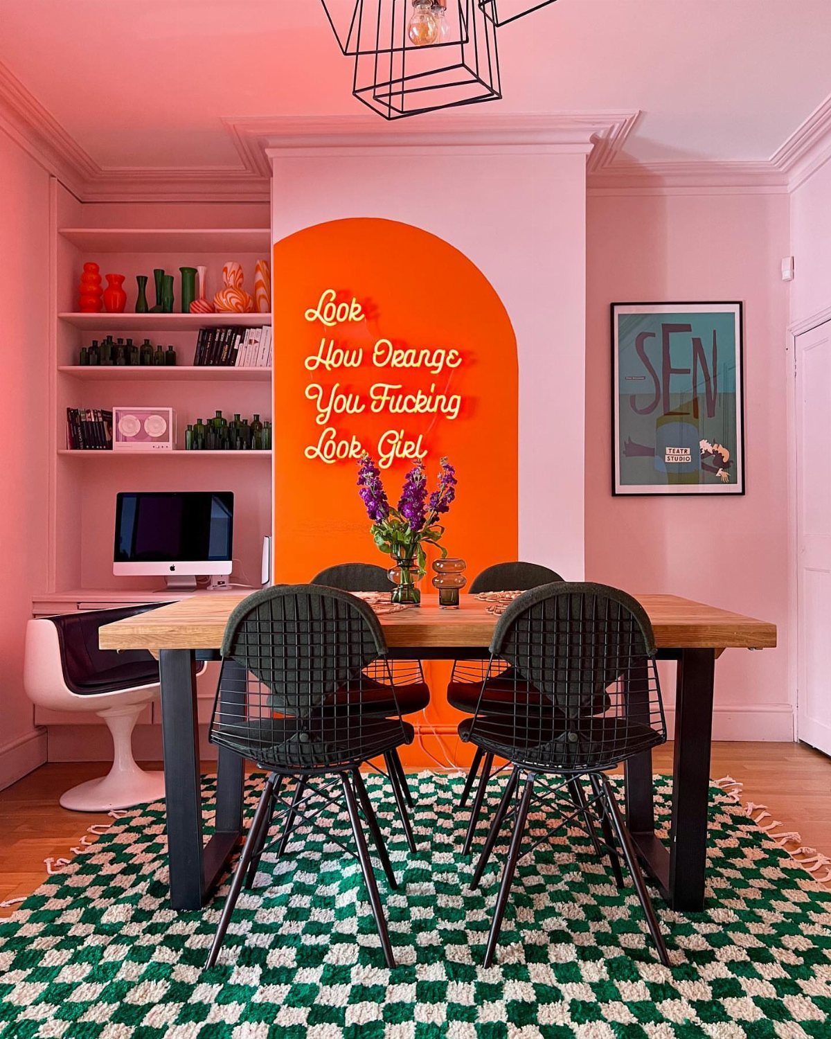Pink and orange walls in a modern office with a checkered green rug.