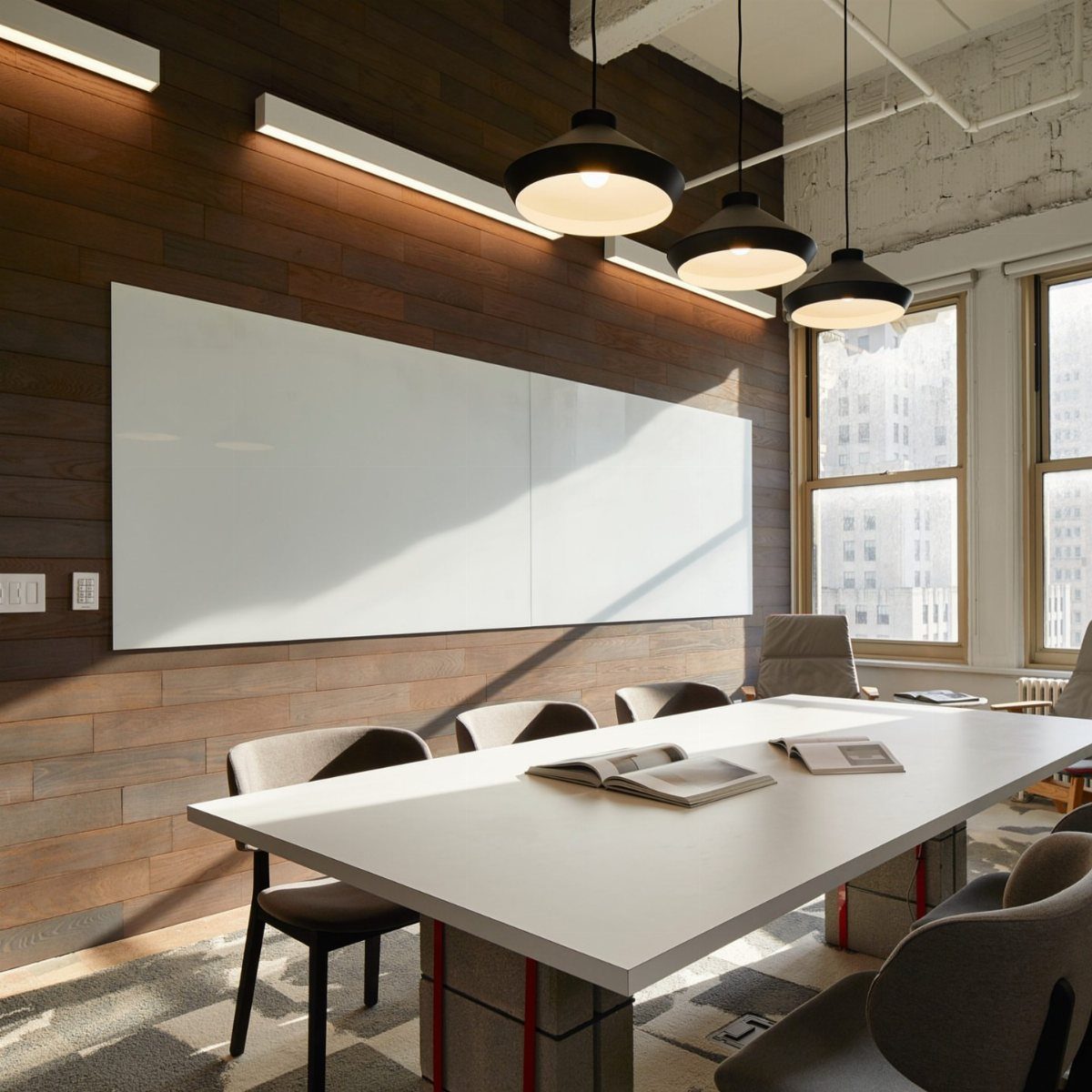 Large white dry erase board on a wood wall in a modern office