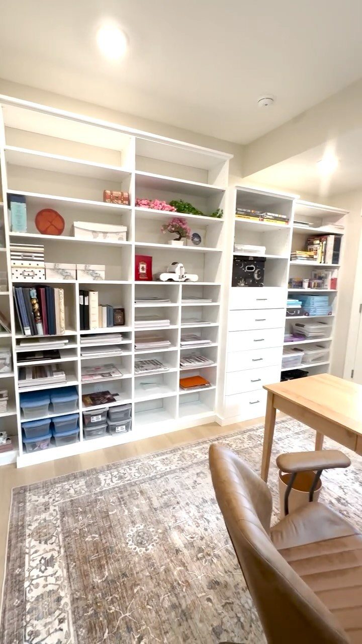 White open shelving units filled with books and bins in a bright office