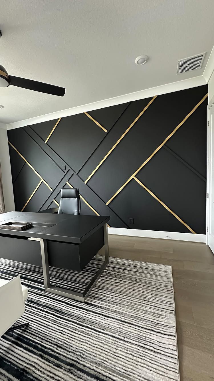 Black accent wall with gold geometric lines in a modern home office.