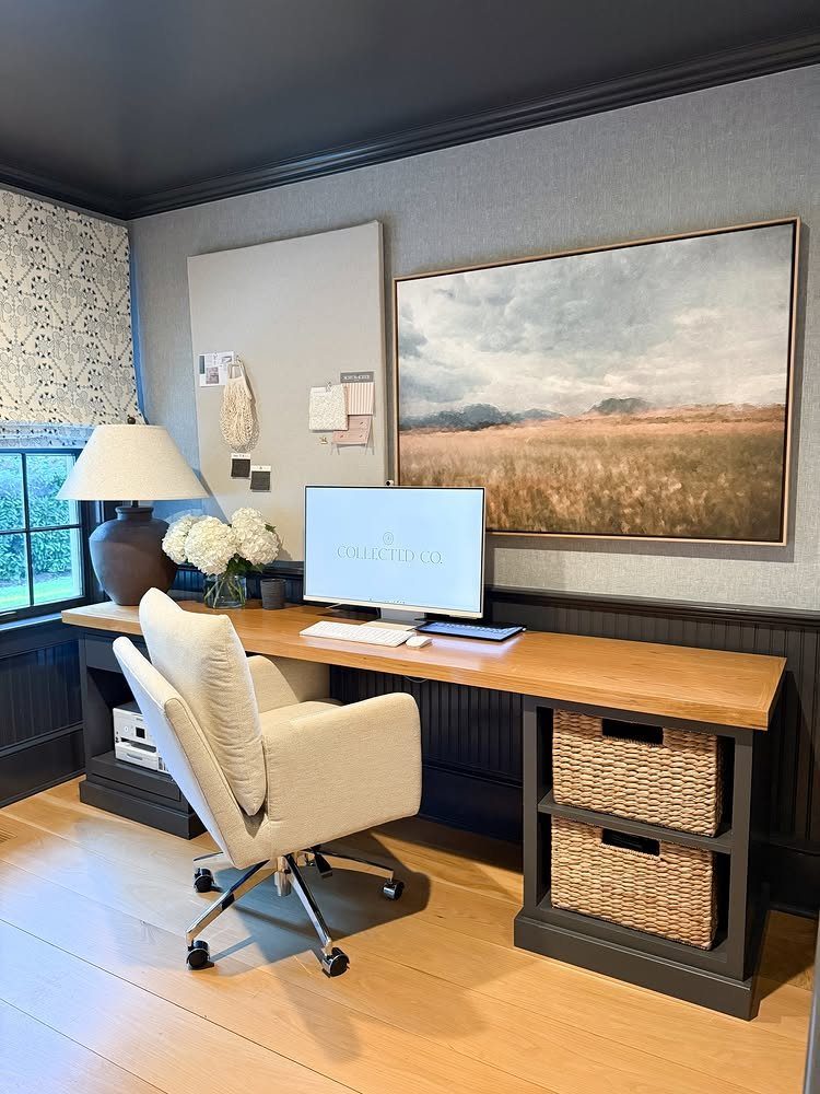 Home office desk with a white bulletin board and large landscape wall art.
