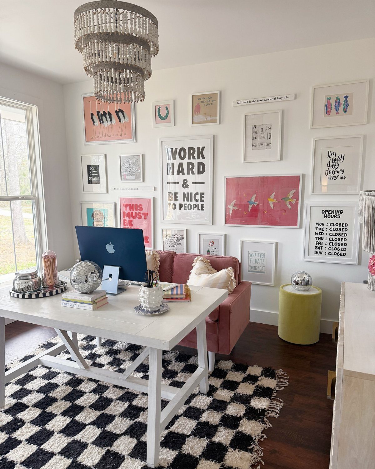 Gallery wall with various framed art and quotes in a bright home office.
