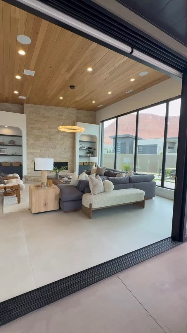 Modern living room featuring floor-to-ceiling glass windows and a wood-paneled ceiling.