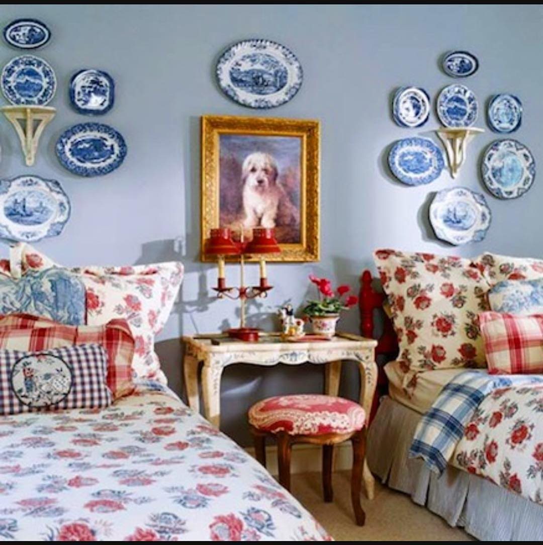 Blue and white decorative plates arranged on a blue wall above two beds.