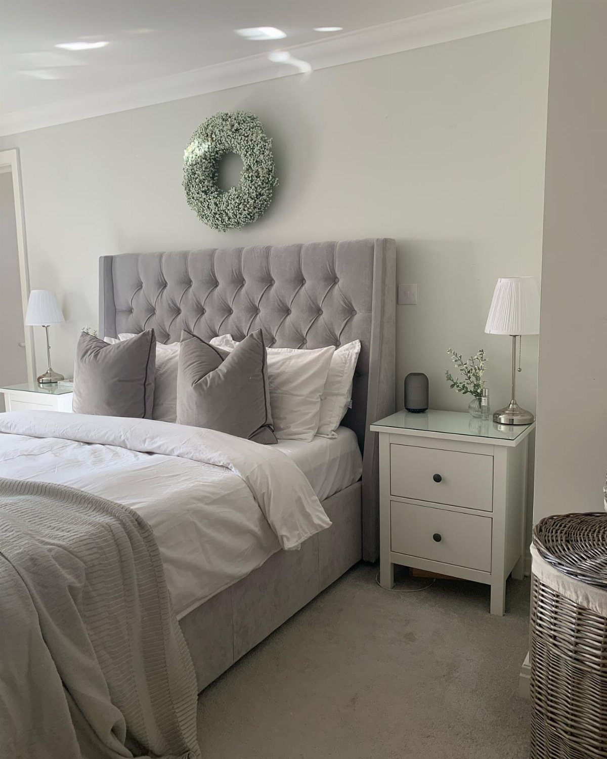 Grey tufted headboard with a green wreath hanging on the wall above it.