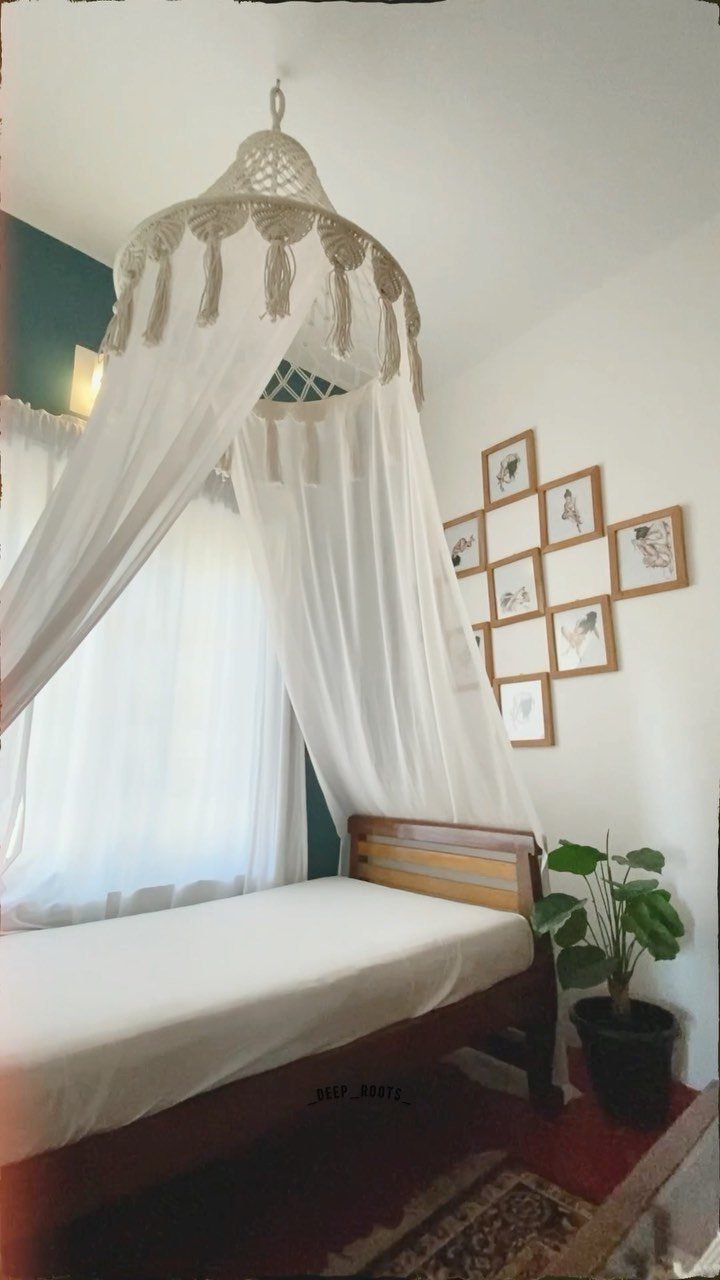 White canopy bed with a cream macrame crown and framed wall art.