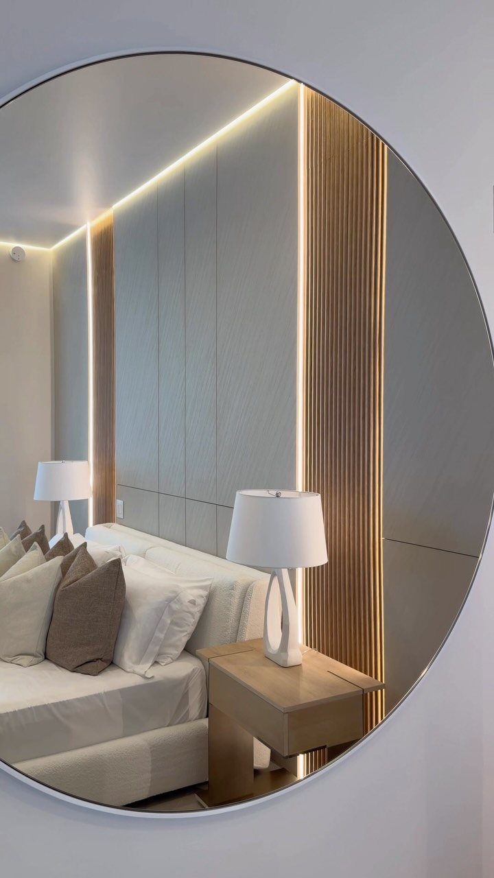 Bedroom reflection in circular mirror featuring vertical wooden wall paneling and warm lighting.