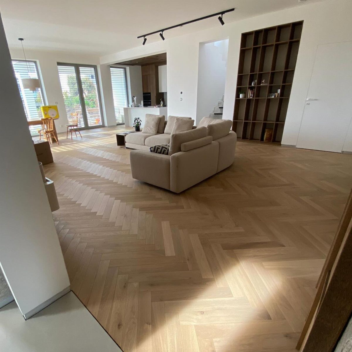 Light wood herringbone flooring in a modern living room with a beige sofa.