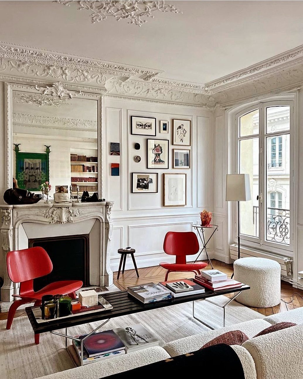 Bright Parisian living room with red modern chairs, white fireplace, and gallery wall.