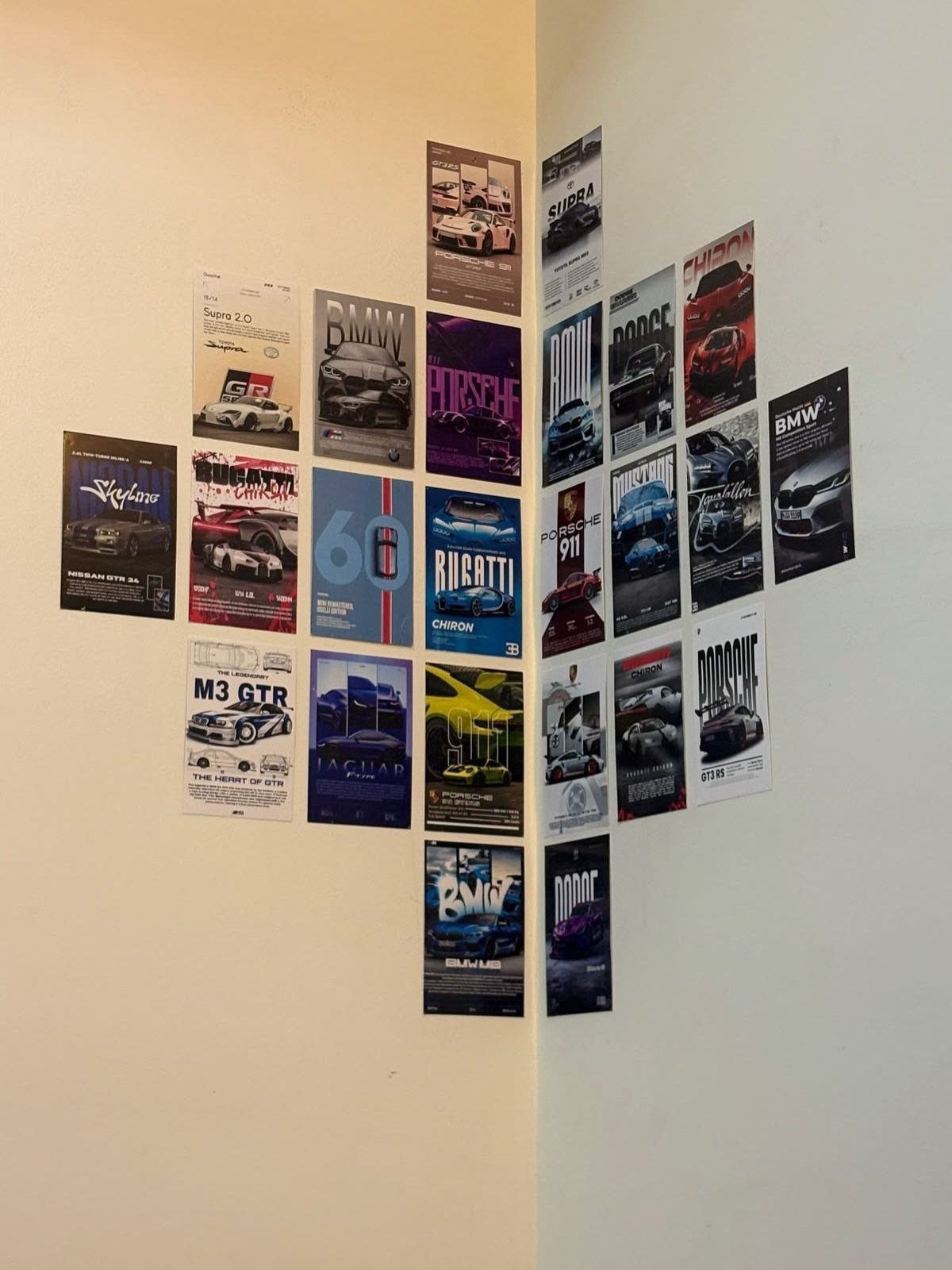 Car posters arranged in a grid layout on a white corner wall.