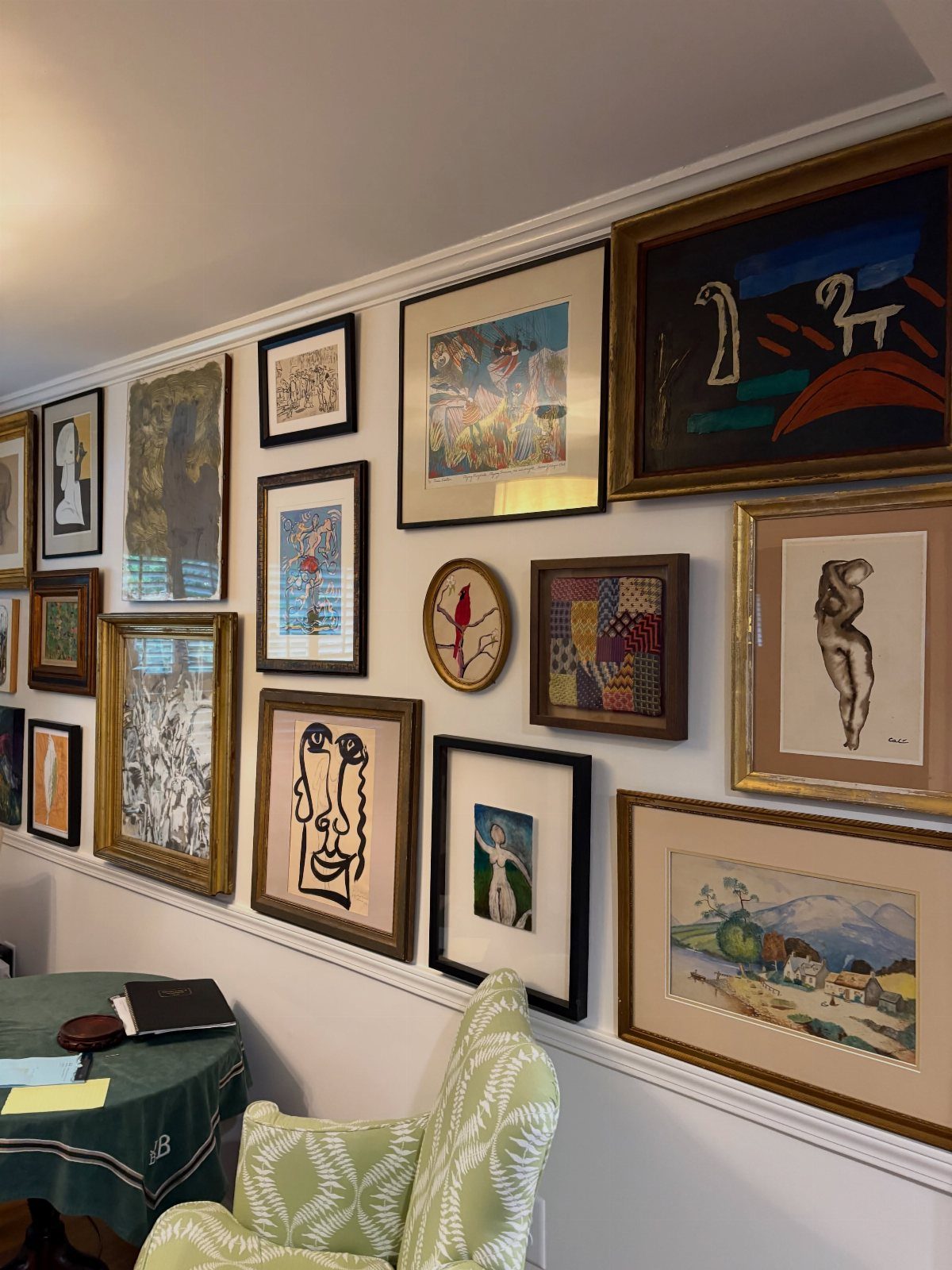 Gallery wall with diverse framed artworks in various sizes and styles on white wall.