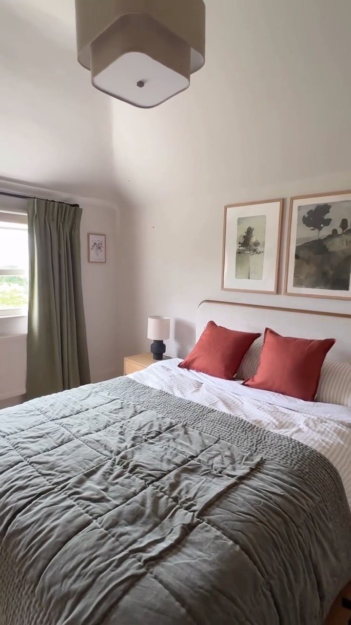 Framed art prints arranged on a white bedroom wall above a bed.