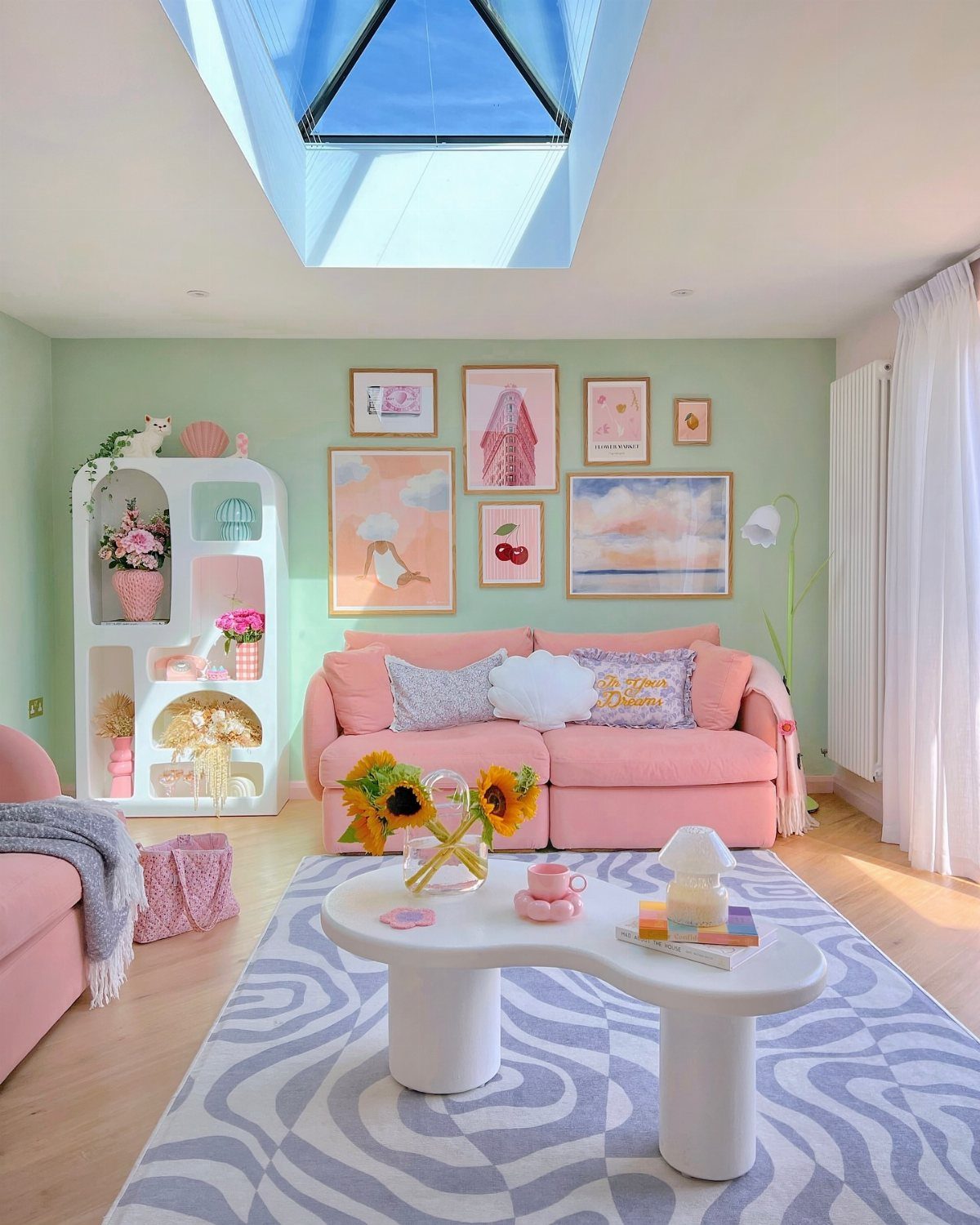 Mint green living room with a pink sofa, white coffee table, and pastel artwork.