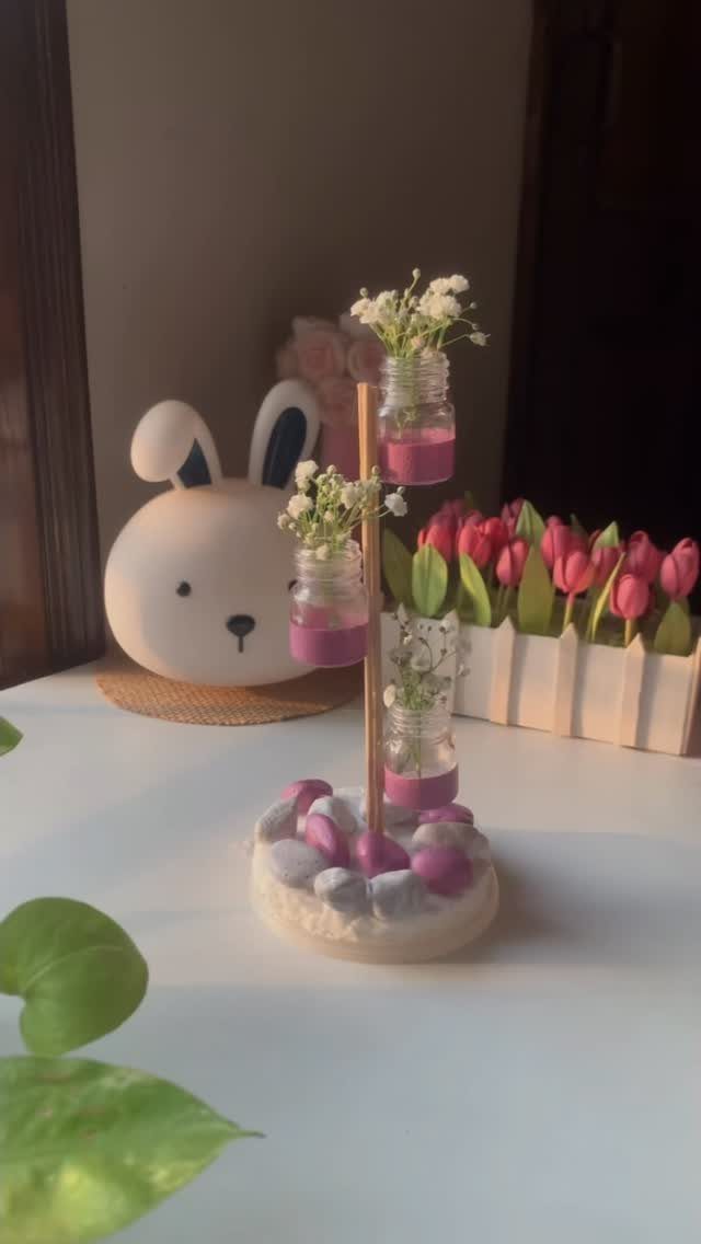 Handmade flower stand with small jars and a bunny lamp on a table