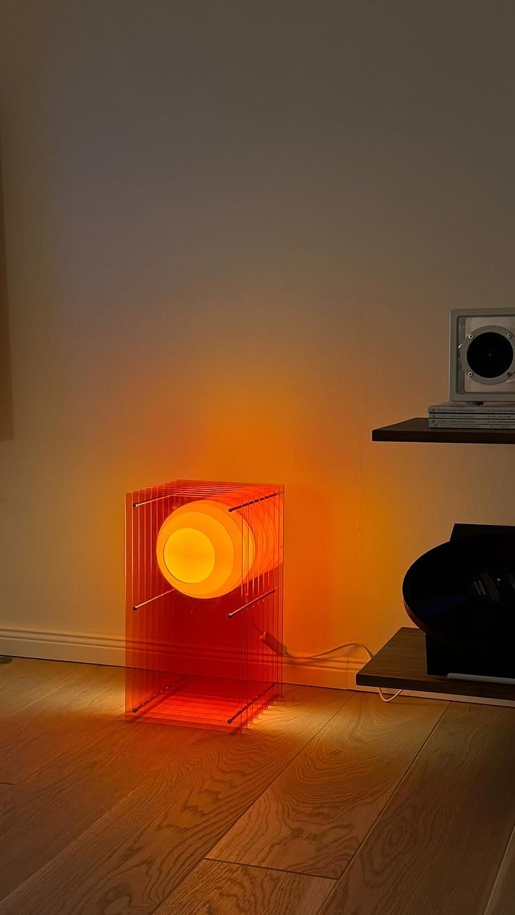 Glowing orange geometric lamp with a spherical light inside a red cubic frame.