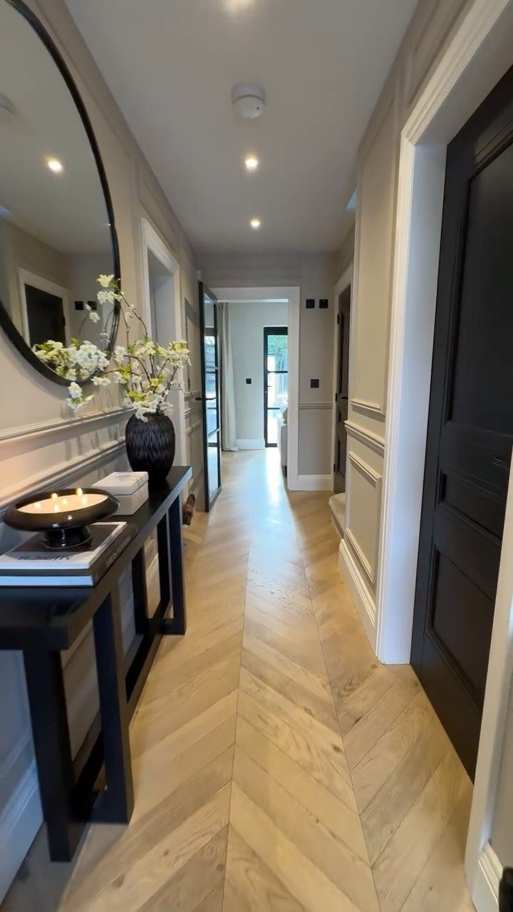 Hallway with herringbone wood floors, grey walls, and a black console table.