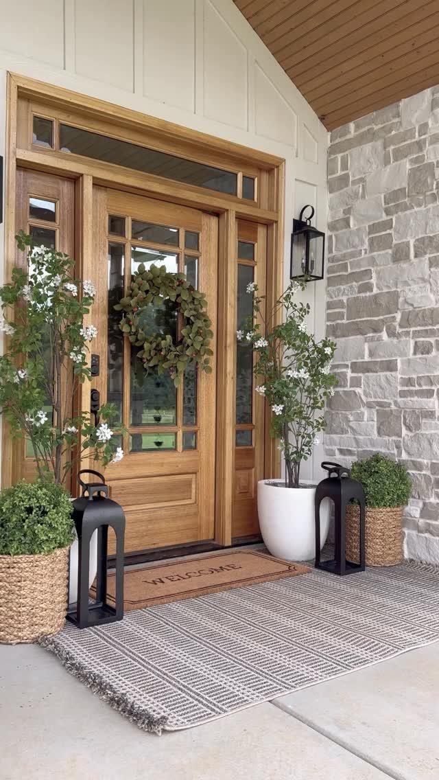 Wooden front door with a welcome mat layered over a larger grey patterned rug.