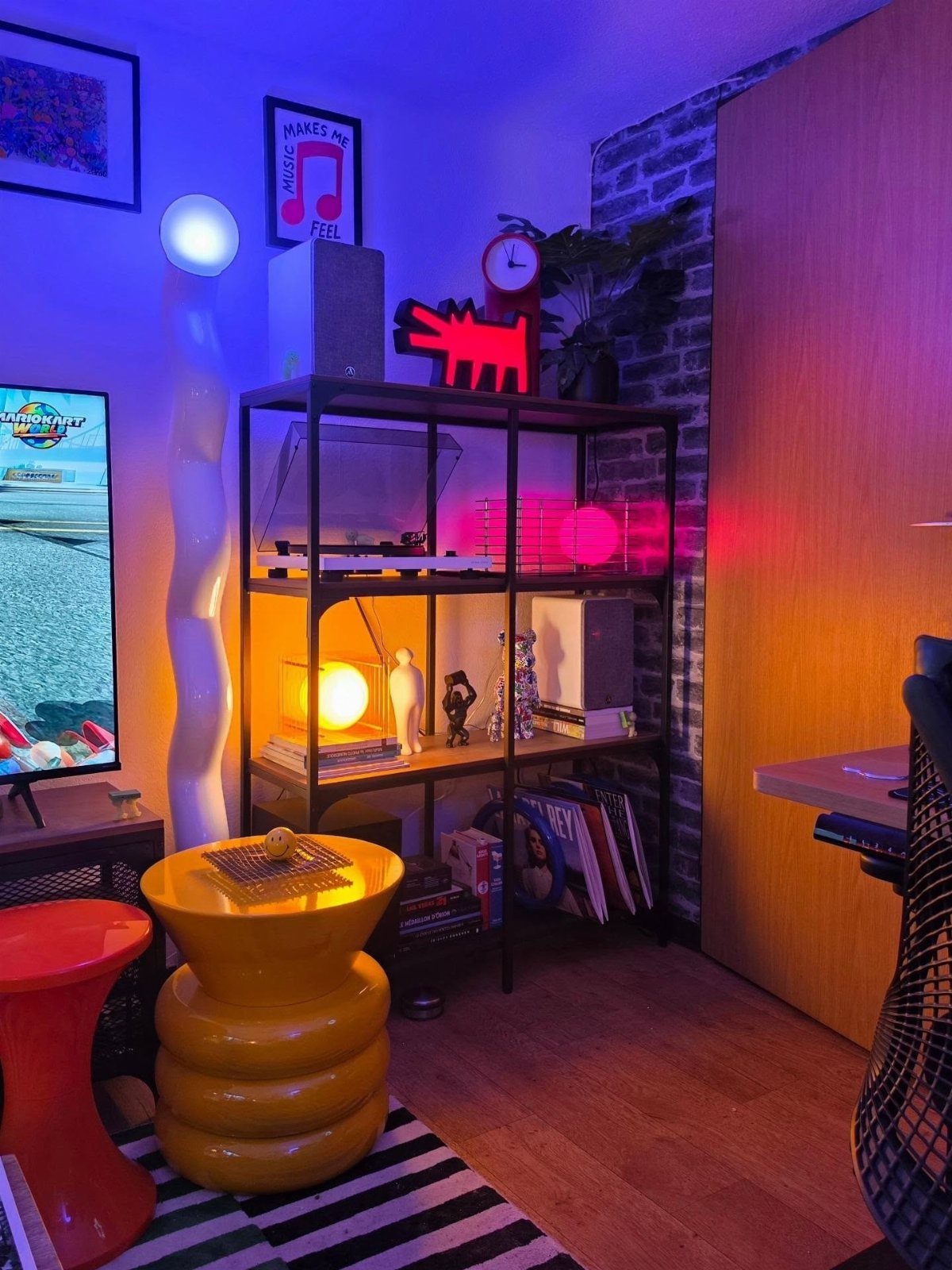 Vibrant room with neon blue and purple lighting, yellow furniture, and metal shelving.