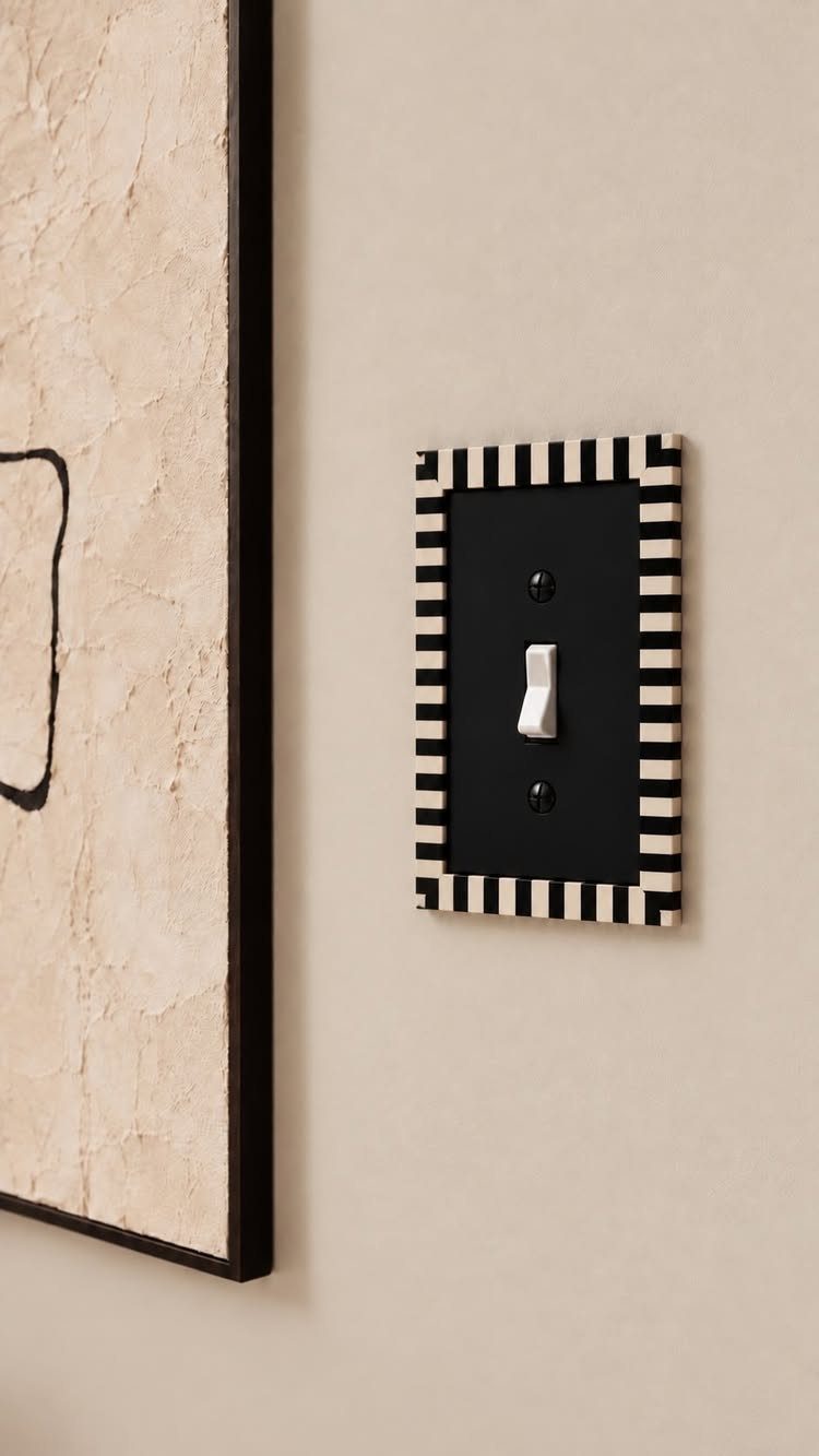 Black light switch plate with striped border on a beige wall.