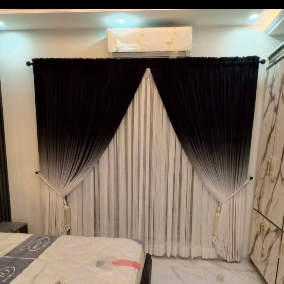 Ombre curtains fading from black to white hanging in a modern bedroom.