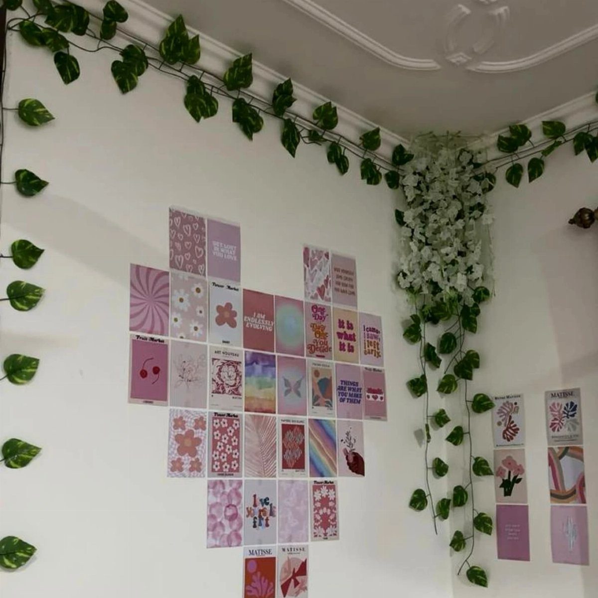 Aesthetic pink and purple photo collage on a white wall with green vines.