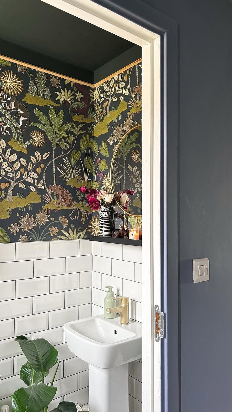 Bathroom with black ceiling, tropical wallpaper, white subway tiles, and white pedestal sink.