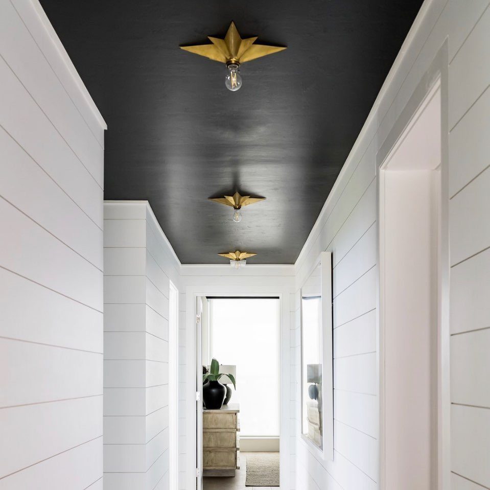 Hallway with white shiplap walls and a black ceiling featuring gold star light fixtures.