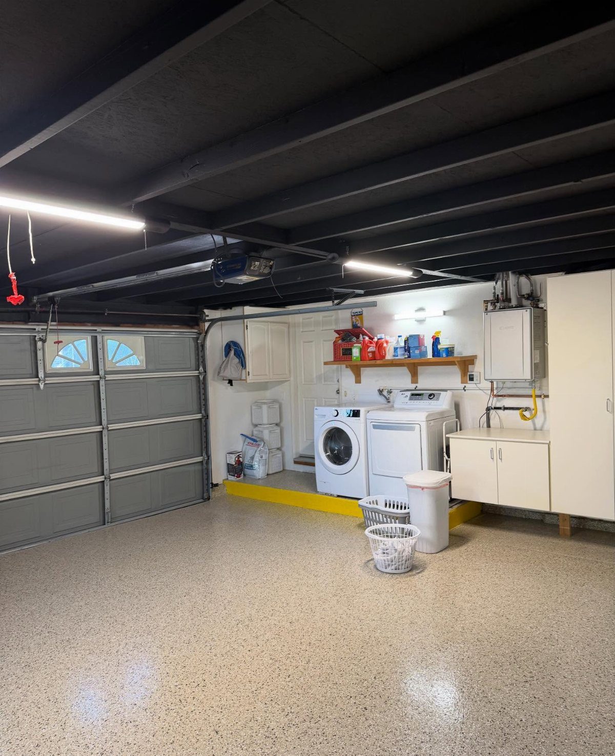Garage interior featuring a black painted ceiling with exposed beams and white laundry appliances.